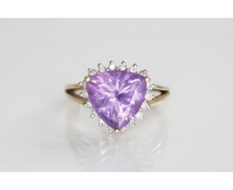 An amethyst and diamond 9ct gold cluster ring, the central triangular mixed cut amethyst measuring 11mm across, with a surrou