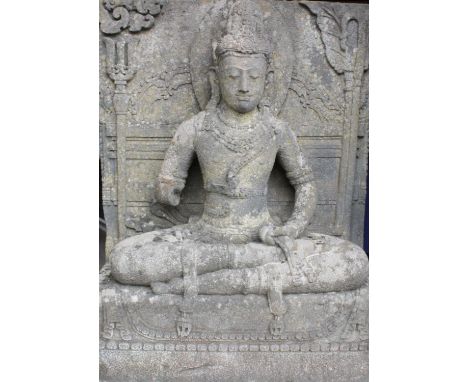 A substantial 19th century carved stone architectural figure of Guanyin, modelled in a seated position with legs crossed upon