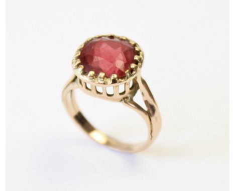 A tourmaline ring, the central orange-pink cushion cut tourmaline (measuring 8.8mm x 8.9mm), claw set in unmarked yellow meta