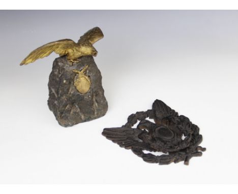 An early 20th century gilt metal figure of an eagle above a ribbon tied oval cartouche, mounted upon a naturalistic granite p