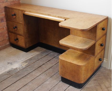 An Art Deco walnut desk, circa 1930, the rectangular top with a central pull-out writing skiver flanked by three drawers and 