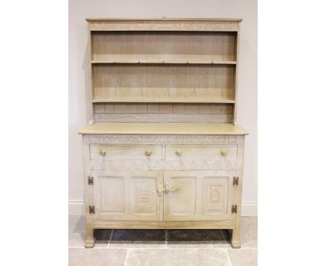 A mid 20th century limed oak Welsh dresser, the high back with a foliate carved frieze over two enclosed shelves, upon the ba