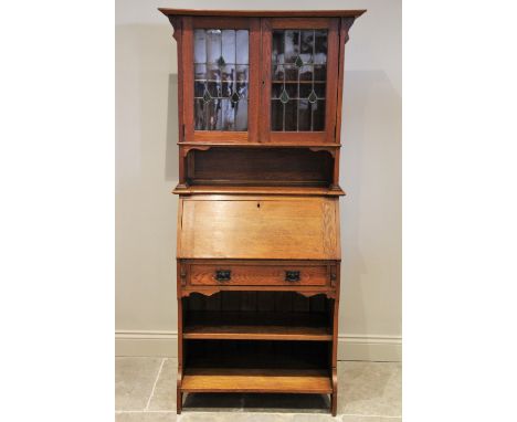 An early 20th century oak Arts and Crafts bureau bookcase, the pair of leaded glass doors opening to a single shelf above a r