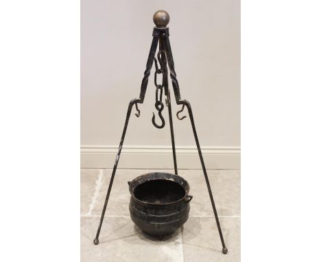 A 19th century iron cauldron and tripod stand, the tripod with a brass spherical finial above three hinged wrought iron suppo
