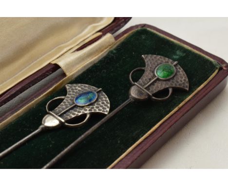 Cased pair of Art Nouveau hat pins with enamelled decoration and hammered Liberty style elements, longest 18cm, boxed. Odd da
