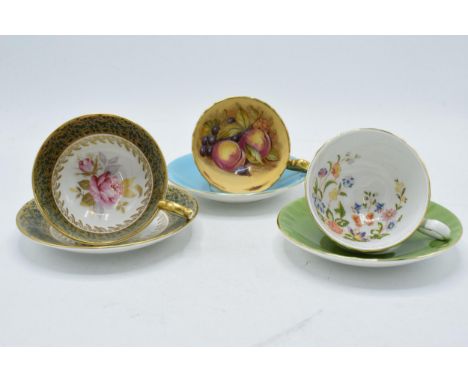 Aynsley cups and saucers to include an Orchard Gold on blue, signed D James, another with a pink rose on the interior and a C