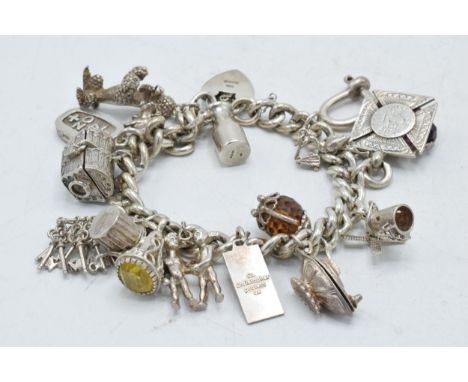 A heavy silver charm bracelet with varying charms to include a swivel fob, a windmill, a magic lantern, a treasure chest and 