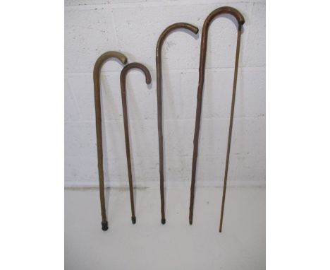 A collection of four vintage wooden walking sticks, along with an alcohol measuring stick