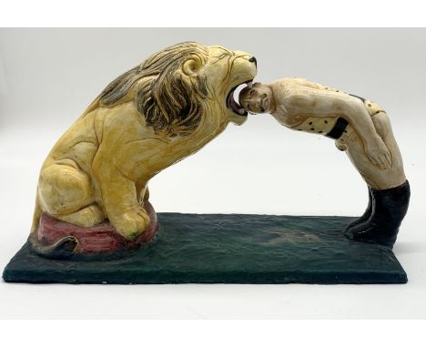 A large ceramic figure of a circus lion and lion tamer with head in his mouth on fibreglass base. Tooth missing as shown and 