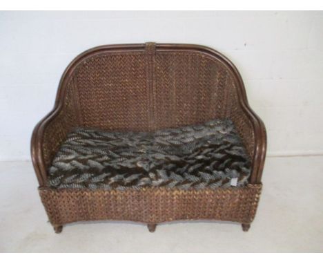 A wicker two seater sofa.