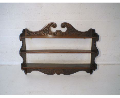 An oak 3 tier wall hanging shelf, with carved decoration, marked 'THS 1915'.