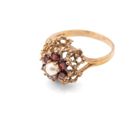 A 9ct gold, garnet and pearl flower head ring, with central pearl surrounded by six garnet petals with further filagree petal