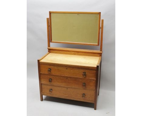 A 20TH CENTURY OAK COTSWOLD ARTS &amp; CRAFTS DESIGN DRESSING TABLE, having mirror back over three long drawers with brass ri