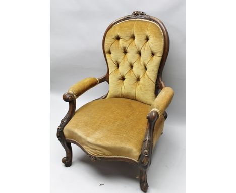 A LATE VICTORIAN CARVED SHOW WOOD FRAMED OPEN ARM DRAWING ROOM CHAIR, having gold fabric upholstered button back, serpentine 