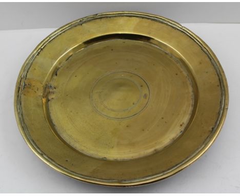 AN 18TH CENTURY DISH, possibly a bronze alms dish, raised on four lug feet, simple ring decoration to centre, 27cm diameter 