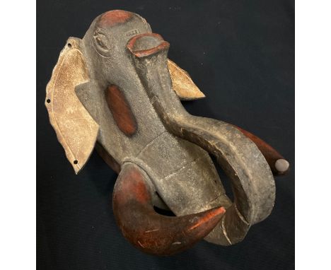 An African tribal zoomorphic elephant mask, possibly Nigerian, shaped curled trunk, three holed ears, textured grey face, cre