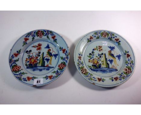 Two Lambeth polychrome delftware plates, circa 1760, each painted with a parrot perched in branches beside a rock and flowers
