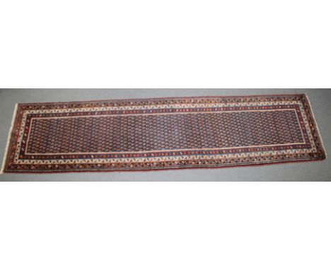 A LONG PERSIAN RUNNER RUG rich blue ground with Boteh decoration. 40cm x 108cm.