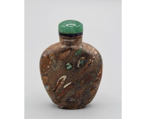 Chinese snuff bottle.Puddingstone of flattened shield shape supported on a raised foot, the matrix suffused with opal and oth