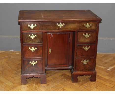 A 19th century mahogany kneehole desk, the rectangular top over an arrangement of seven drawers with brass batswing drop hand