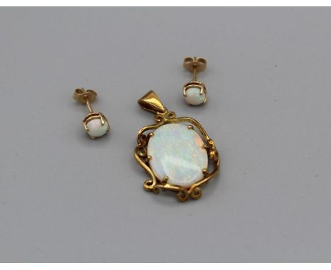 An Australian opal pendant and earring set featuring a 17mm and 13mm opal cabochon in a yellow metal ornate setting, stamped 