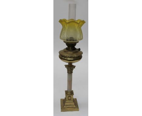 An Edwardian paraffin lamp with frilled lemon tinted etched glass shade, brass reservoir on Corinthian onyx and brass column,