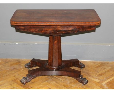 An early Victorian rosewood and crossbanded card table carried on a faceted column, raised on a platform base, paw feet and c