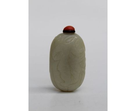 A 19th Chinese leaf carved jade snuff bottle with coral bead stopper, 7cm