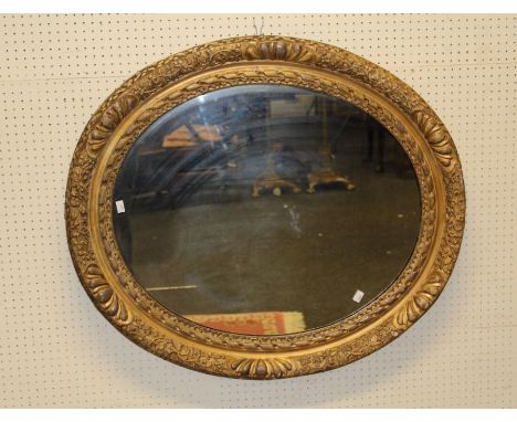 A large 19th century gilt gesso oval portrait picture frame with moulded floral decoration, enclosing a later mirror glass, 9