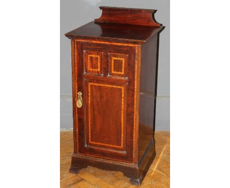 An Edwardian mahogany, satinwood banded pot cupboard, with shaped upstand and three panel door enclosing single shelf, on bra