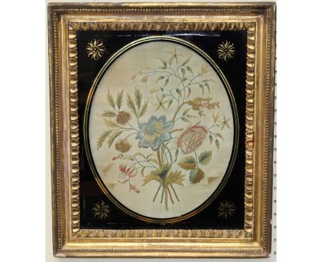 An early 19th century floral silkwork, the oval panel in verre eglomise frame, 36 x 32cm (total)