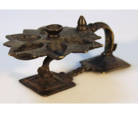 A brass candlestick, the moulded handle aside an inverted foot with an upper floral dish holder, centred by a plain well, pro