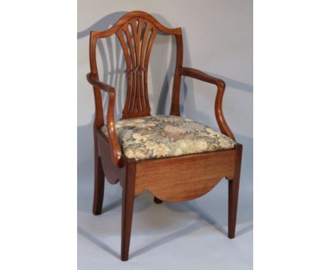 A 19thC mahogany commode chair, with a shield back and pierced splat, raised above a drop in seat with (later) floral materia