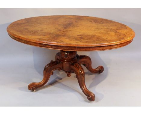A Victorian walnut loo table, the oval top with a moulded crossbanded outline raised on a carved baluster stem terminating in