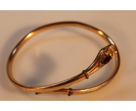 A Serpentine bangle, with red paste stone, hollow rolled gold, 7.5cm wide.