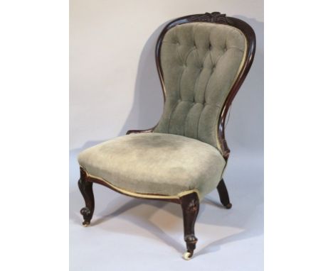 A Victorian mahogany nursing chair, the moulded ebonised back carved with stylized scrolls above an over stuffed seat in (lat