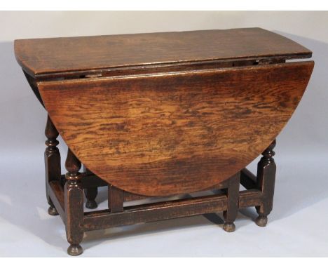 A principally 18thC oak drop leaf gate leg table, the circular top raised on turned supports terminating in bun feet, when cl