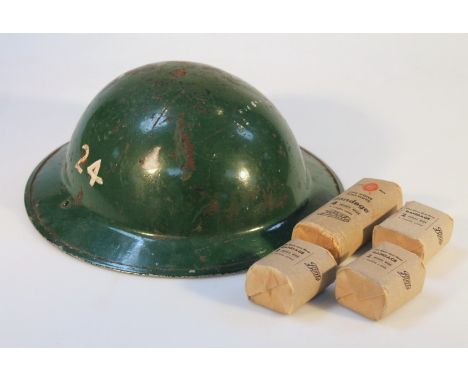 A British army tin helmet, of circular form in green, with leather insert. 31cm wide, and a small quantity of bygone bandages