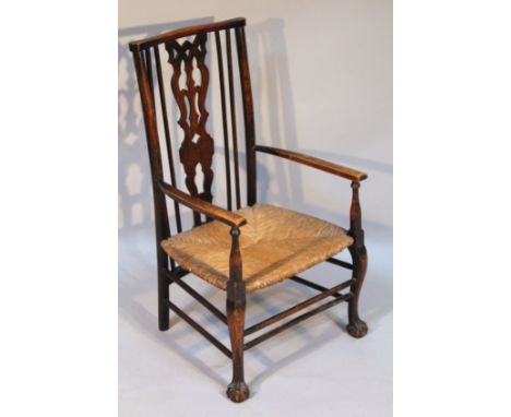 An early 20thC rush seated child's chair, with a pierced back splat, surmounted by a comb shape top rail, above curved arm ra