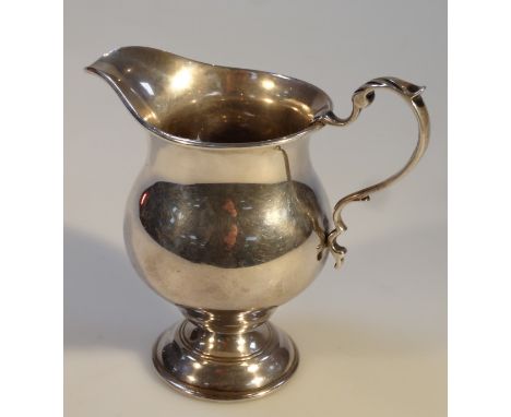 A George V silver cream jug, by Mappin & Webb Ltd, of helmet shaped form, with a bulbous body and C scroll handle on circular