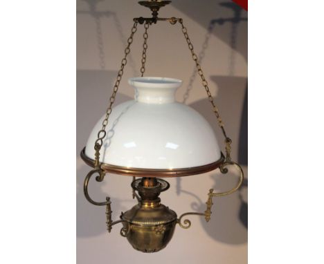An early 20thC hanging brass oil lamp, centred with a part gadrooned dish top, with a sparse floral banding with shaped scrol