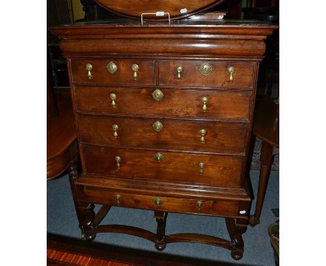 An 18th century oak straight fronted chest of drawers with a cushion shaped top drawer, raised on a stand, carved supports an