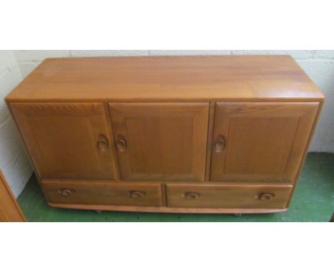 An Ercol Golden Dawn sideboard three cupboard doors above two drawers