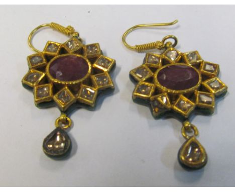 A pair of Indian yellow metal ruby and diamond star shaped earrings with red and green enamel backs