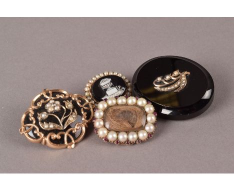 A group of four 19th century and later mourning brooches, including one Georgian example with half cut pearls and garnets, on