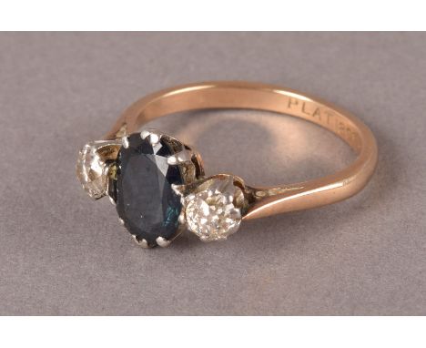 A vintage sapphire and diamond three stone ring, the oval dark blue stone and two old cuts in platinum claws on an 18ct gold 