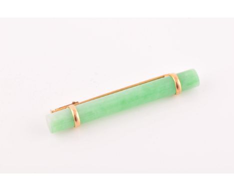 A yellow metal mounted jade bar brooch, set with a polished green jade baton 5.8 cm long, mount unmarked, 9 grams. 
