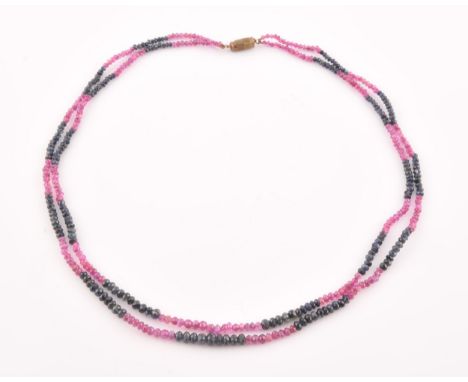 A double strand necklace of faceted ruby and sapphire beads, approximately 45 cm long, fastened with a base metal screw clasp