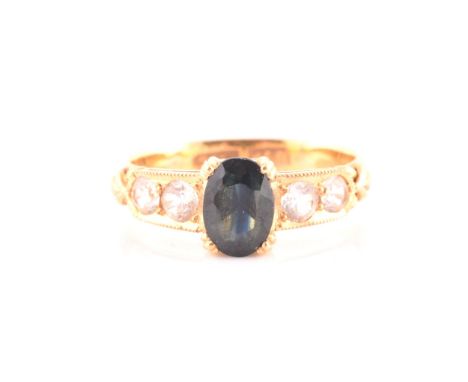 A Chinese 22ct yellow gold ring, set with a mixed oval-cut dark greenish-blue sapphire, the shoulders set with four round-cut