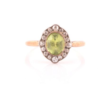 A late 19th century peridot and diamond cluster ring, centred with a mixed oval-cut peridot, the border inset with old-cut di